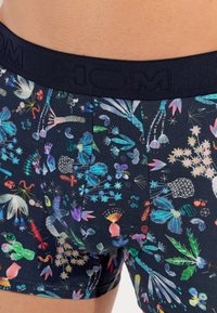 Bóxer de algodón en azul marino con patrones florales y abstractos coloridos. Presenta una cinturilla texturizada con la marca "HOM".