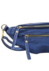 Sac en cuir synthétique métallisé bleu marine avec doubles zips dorés, bandoulière réglable et accents dorés. Surface texturée avec finition brillante.