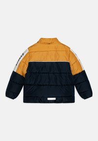 Doudoune avec une partie supérieure jaune et une partie inférieure bleu marine. Caractéristiques : manches longues, col à boutons-pression et détail blanc sur la manche gauche.