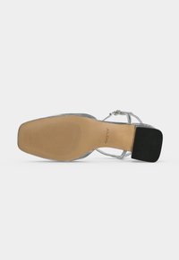 Sandale argentée à brides avec bout carré, talon bloc bas et semelle marron affichant le nom de la marque ALDO.