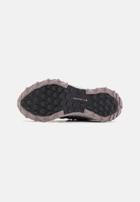 Suela de zapatilla de trail con una superficie de goma negra texturizada, que presenta tacos hexagonales pronunciados para mejor agarre y una entresuela de color rosa claro. Se puede ver la marca Columbia.