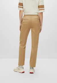 Housut vaaleanbeigeissä, slim fit -mallissa, joissa on takataskut, hopeiset yksityiskohdat ja sileä, kevyt materiaali.