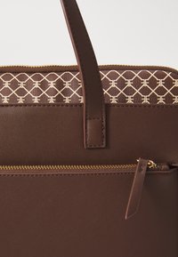 Sac à main en cuir marron foncé avec une fermeture éclair dorée, une anse cousue et un panneau supérieur avec un motif géométrique beige.