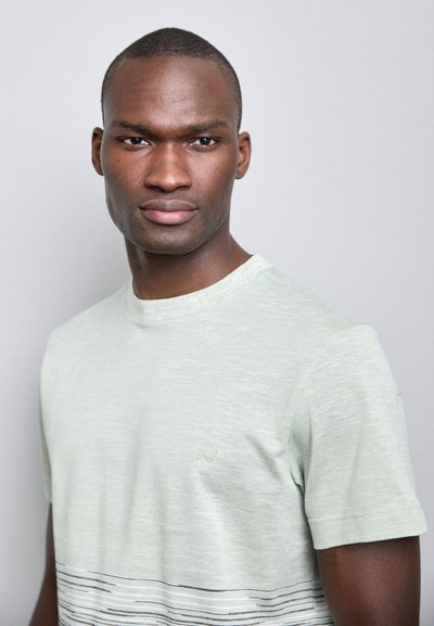 Lysegrønn kortermet t-skjorte med teksturert finish, med horisontale svart-hvite striper. Enkel rund hals, diskret logodetalj.