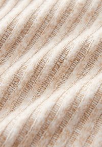 Beige geripptes Strickgewebe mit einem strukturierten Muster aus abwechselnd dicken und dünnen Streifen, was Tiefe und visuelles Interesse erzeugt.