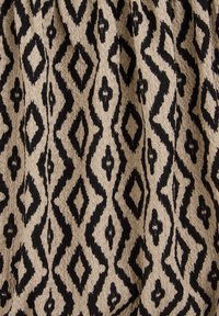 Textilie s diamantovým vzorem v černé barvě na béžovém pozadí, vyrobená z tkaniny s texturovaným povrchem.