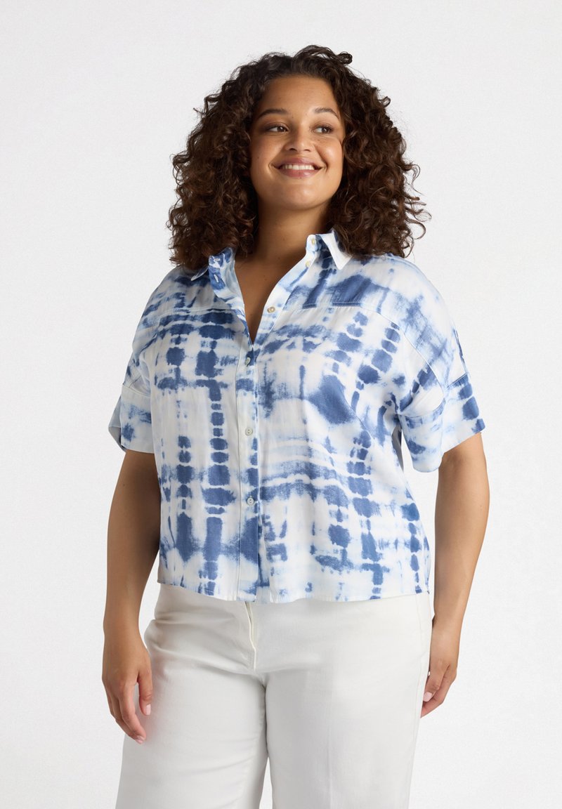 Camicetta a maniche corte, con bottoni, in un motivo tie-dye bianco e blu, realizzata in tessuto leggero con vestibilità rilassata e orlo leggermente arrotondato.