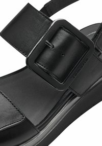 Sandalo nero con una fascia larga e una grande fibbia rettangolare. Texture in pelle liscia con dettagli di cucitura discreti e una suola a zeppa bassa.