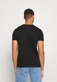 Svart kortermet t-skjorte laget av bomull, med rund hals og enkel design. Kombinert med lyseblå denimjeans.
