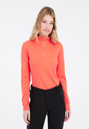 Langärmliges, hochgeschlossenes Hemd in leuchtendem Orange mit einem halben Reißverschluss vorne. Aus weichem, dehnbarem Material, kombiniert mit schwarzen Hosen und einem minimalistischen Logo.