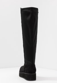 Zwarte kniehoog laars met een gladde synthetische bovenkant en een getextureerde suede teen. Platformzool en zijsteekdetails.