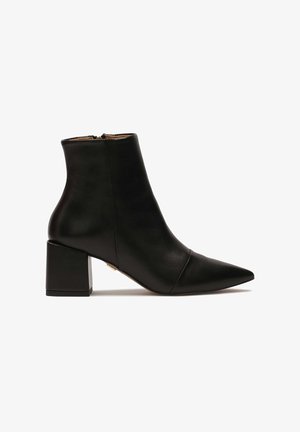 Fekete bőrből készült bokacsizma hegyes orral, blokk sarka, és hátsó cipzárral. Simább felület, minimális varrási részletekkel.