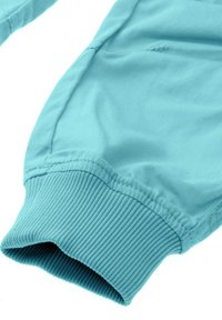 Turkusowa bluza z długim rękawem, z ribbowanymi mankietami zapewniającymi dopasowanie, gładką teksturą materiału oraz prostym, czystym designem.