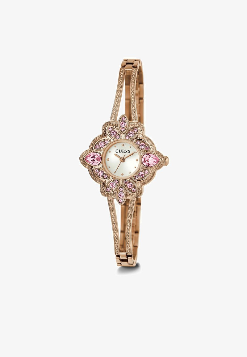 Aranyszínű óra virág alakú tokban, fehér számlappal és rózsaszín kristály díszítéssel. Karcsú karkötőszíj, texturált láncszemekkel.