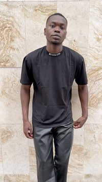 Must mustvalge T-särk, mille krael on kirjutatud "Brooklyn", koos läikivate mustade kunstnahkpükstega, millel on tekstuuriline muster.