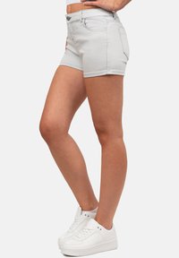 Shorts en denim gris clair au design ajusté, avec cinq poches et des accents cousus, associés à des baskets de sport blanches.