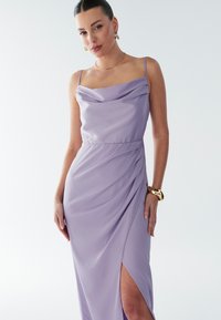 Lavendli lilla satiinist kaelusega kleit, millel on volditud detailid ja reie kõrgune lõhik. Omab õhukesi rihmasid ja keha järgivat lõiget.