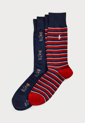 Tre paia di calzini: blu navy con ricamo di orso, a righe rosse e blu navy, con accentuazione rossa sulla punta, tutti con una texture di maglia morbida.