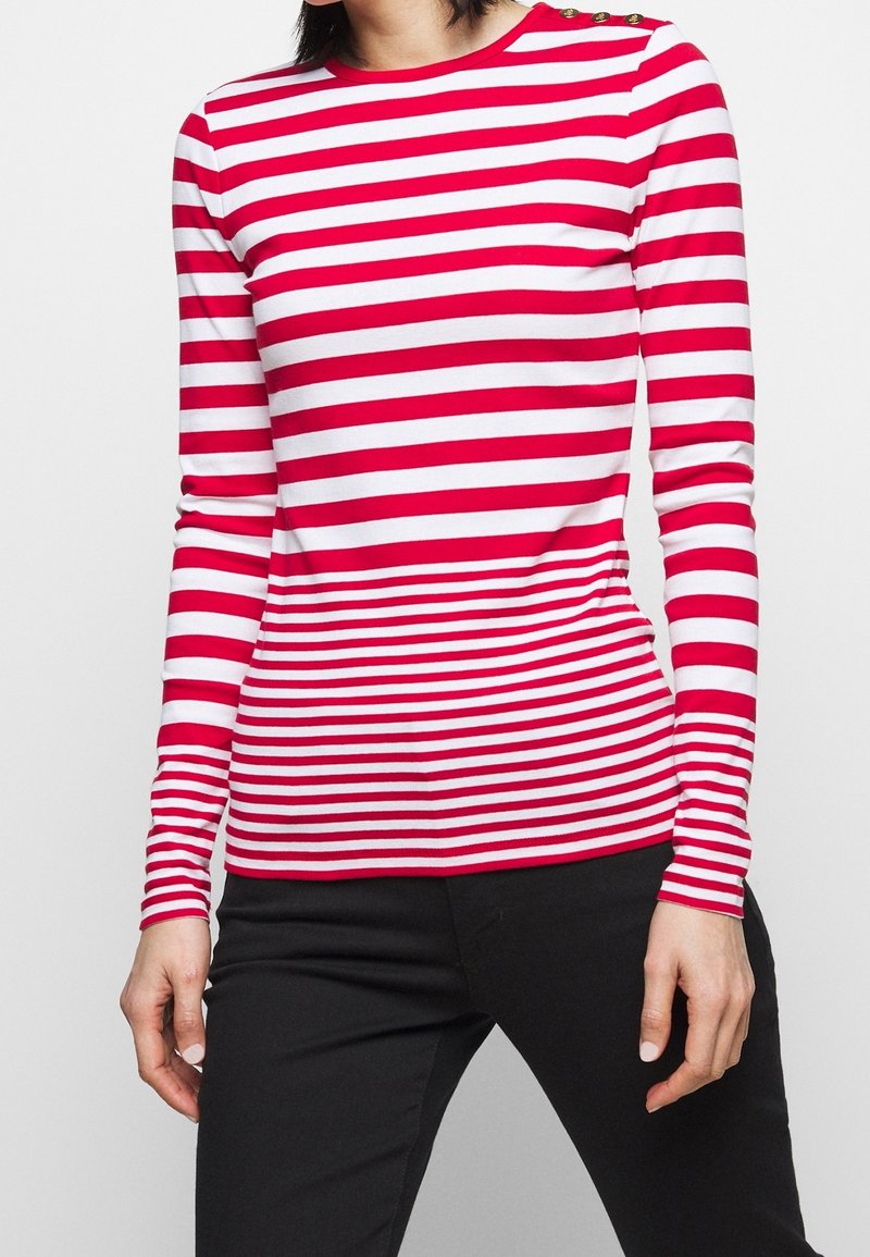 Czerwona i biała w paski koszula z długim rękawem, okrągłym dekoltem i guzikami na ramieniu, wykonana z gładkiego, elastycznego materiału.