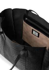 Svart läder tote bag med en texturerad krokodilsmönster. Inuti finns en beige dragkedjeficka med ett geometriskt mönster och varumärkesetikett.