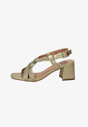 Sandaña dorada con tacones, correas de tejido trenzado y una hebilla ajustable en el tobillo. Diseño de punta cuadrada con un tacón grueso. Forro interior suave.