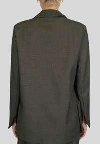 Blazer verde scuro con tessuto strutturato, revers a punta e spacchi laterali. Presenta una vestibilità sartoriale e maniche lunghe. Vista posteriore mostrata.
