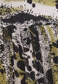 Mönstrad tyg som har abstrakta svarta och olivgröna mönster på en krämfärgad bakgrund med plisserad textur och varierande linjetjocklek.