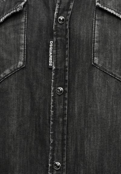 Μπροστινή όψη μαύρου τζιν πουκάμισου με μεταλλικά κουμπιά τύπου σούστα, δύο τσέπες στο στήθος και κάθετη υφασμάτινη ετικέτα DSQUARED2 στη λωρίδα με τα κουμπιά.