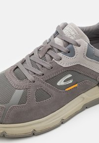 Gray sneaker made of mesh and suede, featuring a textured design, lace closure, and subtle orange accent near the sole.