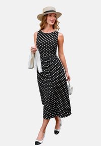 Czarna midi sukienka w kropki z dopasowanym górą i rozkloszowanym dołem. Posiada okrągły dekolt, połączona z białym kardiganem i butami w dwóch kolorach.