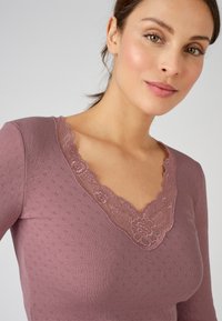 Violet long-sleeve top with a textured pattern, featuring a floral lace V-neckline and a fitted design.