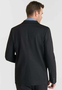 Blazer nero con spalle strutturate, una texture liscia e una fessura centrale sul retro. Presenta cinque bottoni sui polsini.
