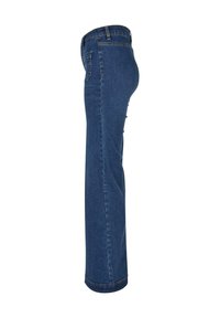 Jean en denim bleu foncé à jambe droite, montré de côté gauche avec couture latérale visible, poche arrière et passants de ceinture, sur fond blanc.