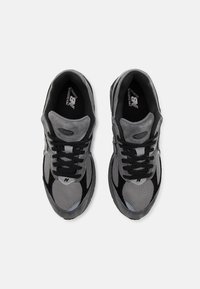 Męskie buty do biegania w szarym zamszu i siateczce, z czarnymi sznurówkami i akcentami. Posiadają teksturowany design oraz logo New Balance na języku.