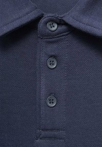 Close-up van een marineblauwe poloshirtkraag met drie donkere knopen en een gestructureerde breiwerkstof.