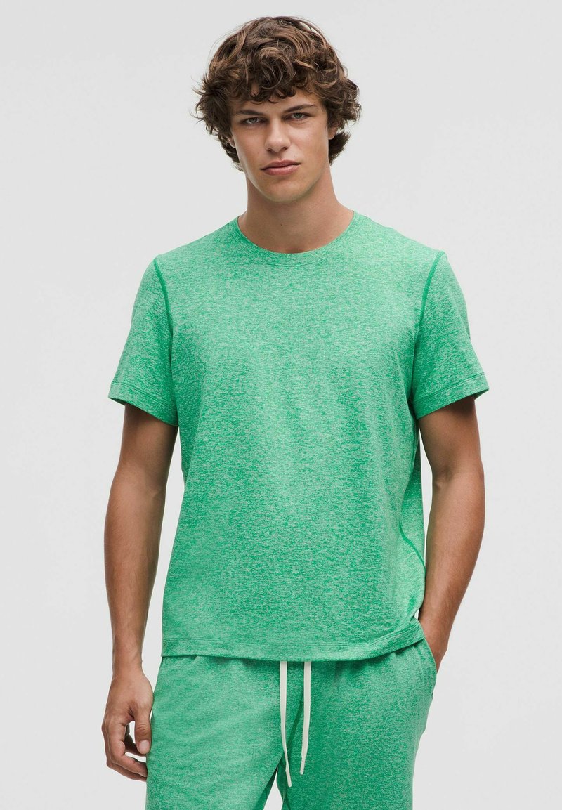 Grünes T-Shirt mit kurzen Ärmeln und strukturiertem, meliertem Muster. Rundhalsausschnitt, lockere Passform und dezente Seitennähte.