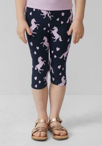 Mariene leggings met een eenhoorn- en hartpatroon, gemaakt van een stretchy stof. Versterkt door een cropped ontwerp en gecombineerd met bronzen sandalen.
