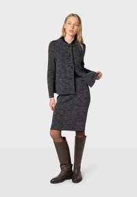 Completo in maglia grigia scura con texture, dotato di giacca aderente, scollatura rotonda e chiusura a bottoni, abbinato a una gonna a tubino lunga fino al ginocchio e stivali marroni alti fino al ginocchio.