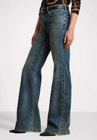 Bredde denim jeans i mørkeblå med falmet vask. Har fem lommer, beltehemper og subtile sømdetaljer ved kanten.