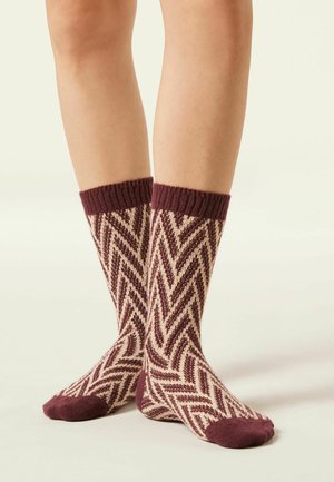 Chaussettes bordeaux et crème montantes, ornées d'un motif à zigzag, avec des bords côtelés et un tissu texturé. Fini doux et confortable.