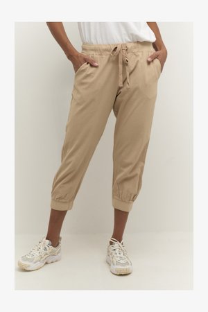 Beige cropped trousers with elastic cuffs and a drawstring waist. Made of soft fabric, featuring side pockets for utility.