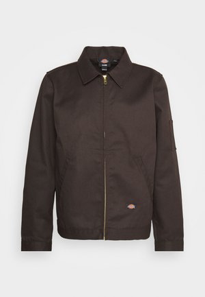 Brun zip-up jakke med krave, sidelommer og et lille logo-patch. Fremstillet af slidstærkt stof med lange ærmer.