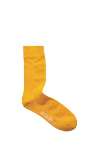 Geel katoenen sok met een geribde boord en een gladde textuur. Voorzien van witte branding op de zool. Eenvoudig ontwerp, zonder patronen of versieringen.