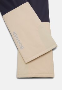 Beige a námořnická modrá svrchní vrstva s hladkou texturou látky. Obsahuje logo "BOGNER" ve světle šedé barvě, kontrastní barevné bloky a čisté linie.
