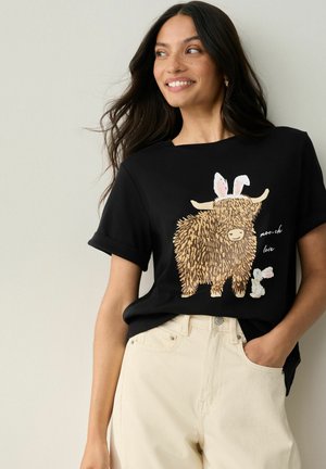 Czarna koszulka z grafiką brązowej, kudłatej krowy i białego królika, z zabawnymi uszami i napisem "moo-ch love". Luźny krój.