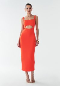 Oranje aansluitende midi-jurk met vierkante halslijn, zijuitsnijding en spaghettibandjes. Glad materiaal en minimalistisch ontwerp. Gouden accent sandalen.