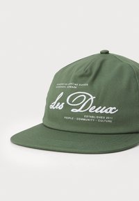 Casquette verte en coton avec un design structuré. Présente un texte brodé en blanc : "Les Deux", "Scandinavian Sporting Goods" et "Established 2011".