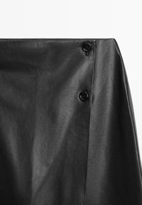 Sort nederdel i kunstlæder med to sorte knapper på højre sides lukning, der viser tekstur og lette folder i materialet.