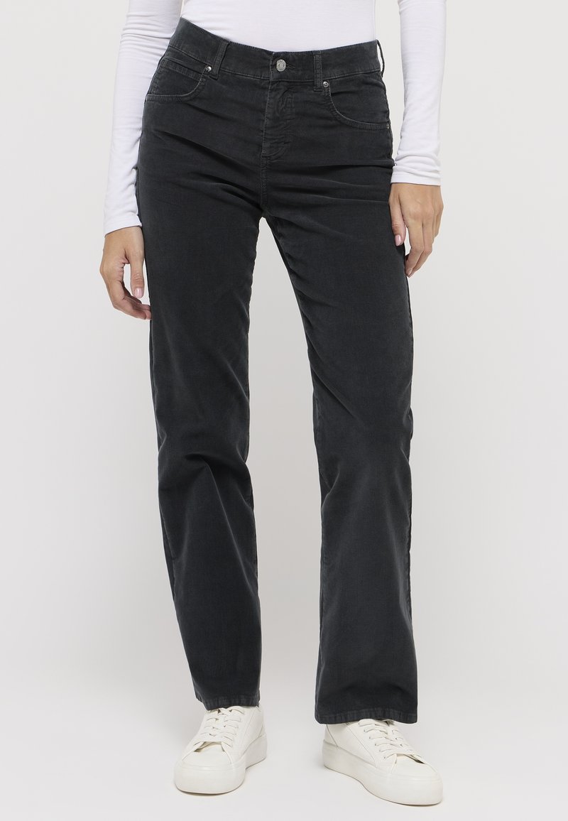 Schwarze Cordhose mit geradem Schnitt; verfügt über Fronttaschen und einen Metallknopf am Bund; kombiniert mit weißen Sneakers.