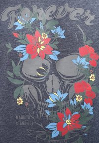 T-shirt grigio scuro con una grafica di teschio decorata con vivaci fiori rossi e blu e la parola "Forever" in grigio chiaro.